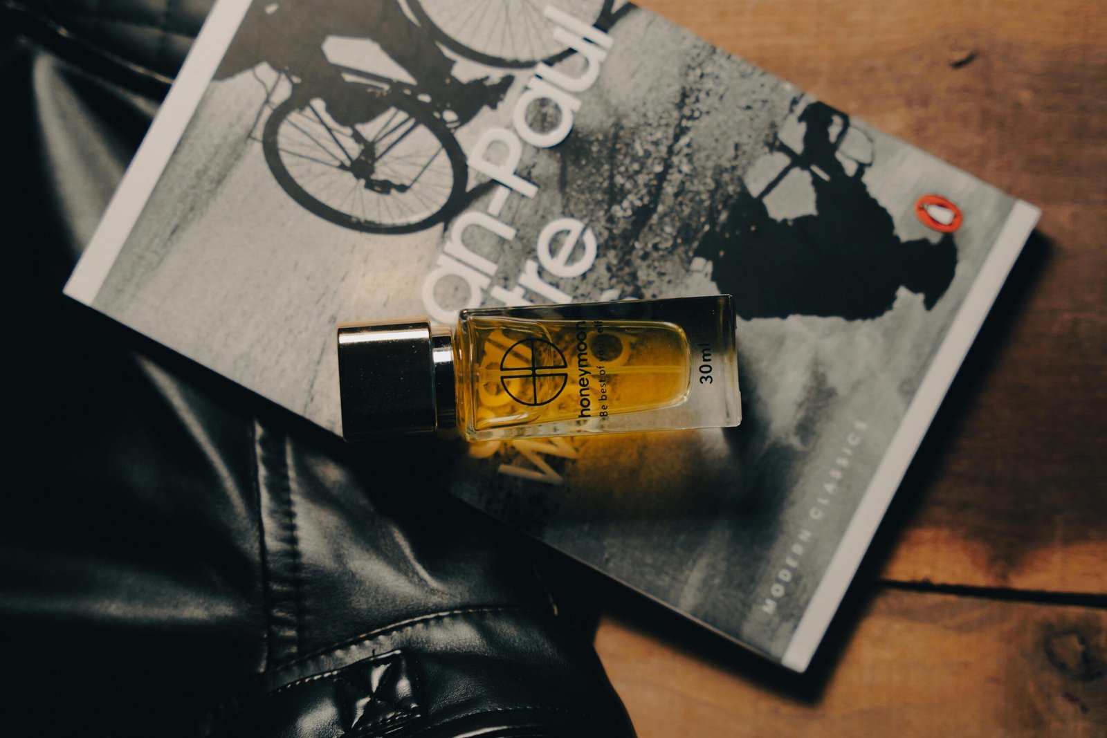 Men's perfume bottle on Jean-Paul Sartre's book in a stylish flat lay fashion.